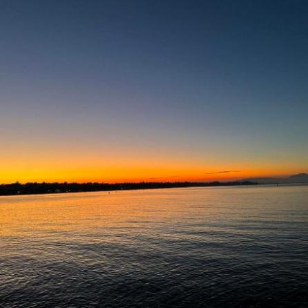 Zonsondergang boven zee met oranje en donkerblauwe lucht.