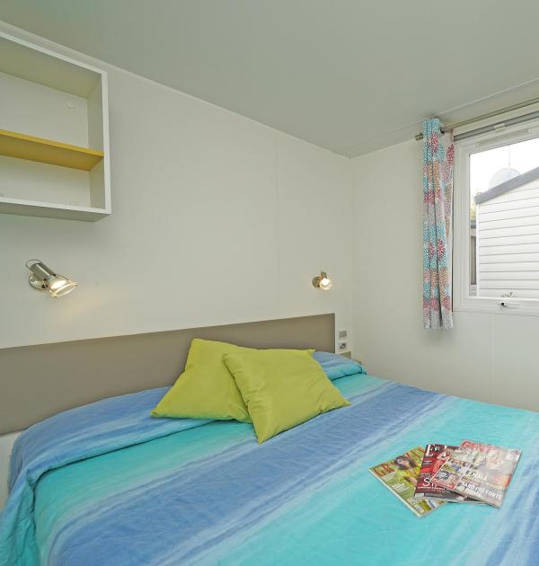 Simple bedroom with double bed and magazines.