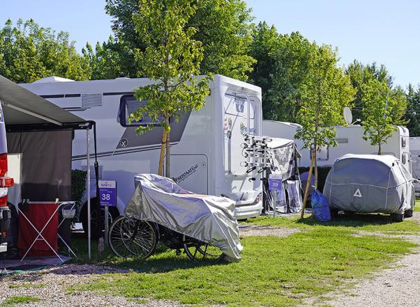 Geparkeerde campers met luifels en hoezen in een groene omgeving.