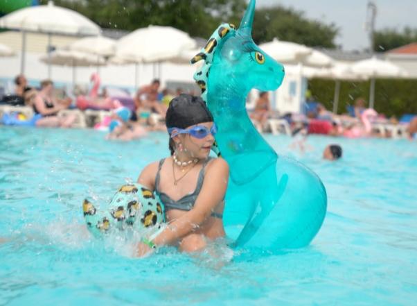 Enfant dans la piscine avec une bouée dinosaure.