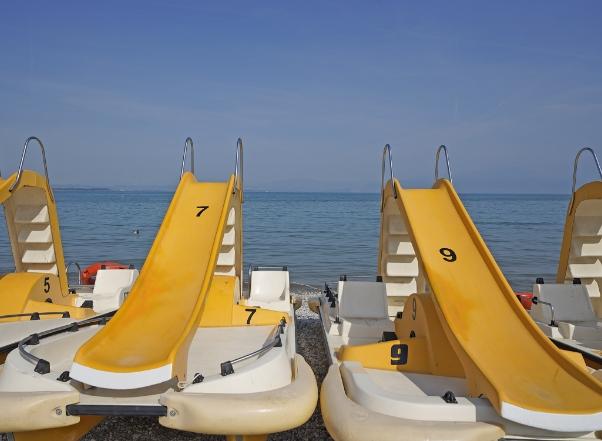 Pédalos jaunes avec toboggans sur la plage, prêts pour la mer.