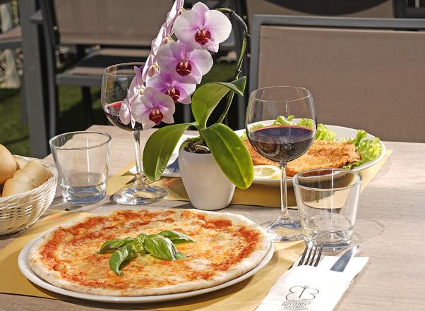 Pizza margherita avec vin rouge et fleurs sur la table.