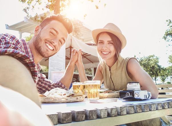 Lachend stel aan buitentafel met eten en bier.