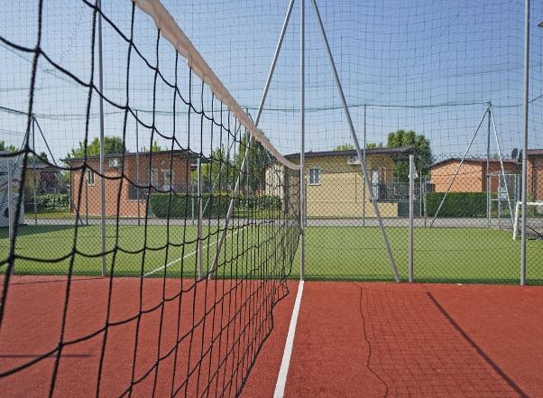 Sportveld met volleybalnet en rode ondergrond.