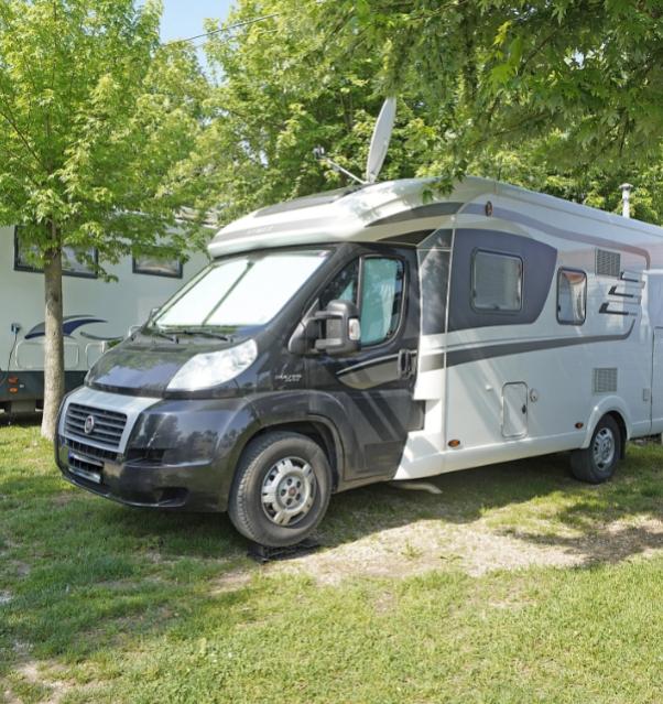 Camper geparkeerd onder bomen, klaar voor avontuur.