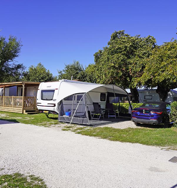 Camping met caravan, auto en bungalows onder een heldere lucht.