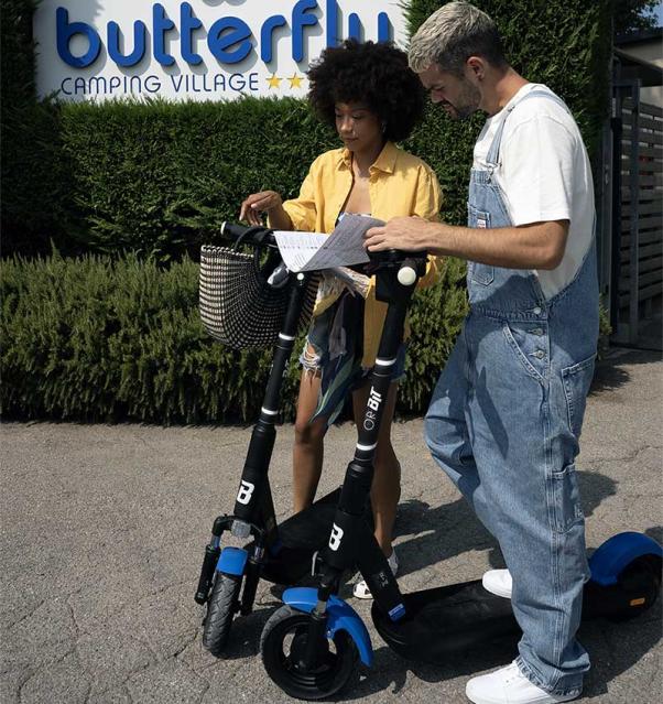 Deux personnes avec des trottinettes devant Butterfly Camping Village.