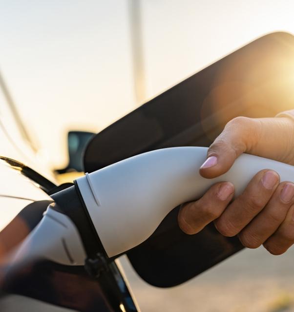 Opladen van een elektrische auto bij zonsondergang.