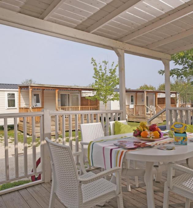 Terras met tafel en stoelen, uitzicht op stacaravans.