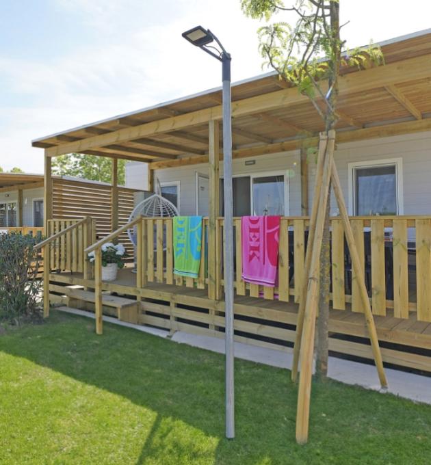 Modern bungalow met veranda, kleurrijke handdoeken en tuin.